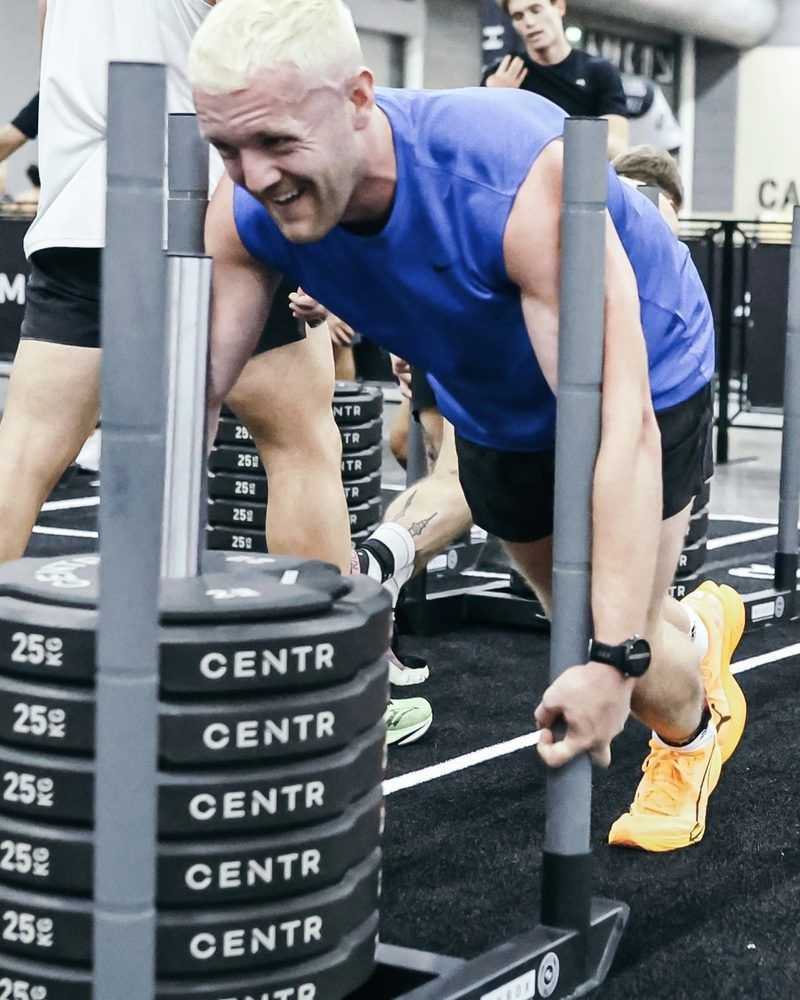 Dan McCaffrey smiling mid sled push at HYROX