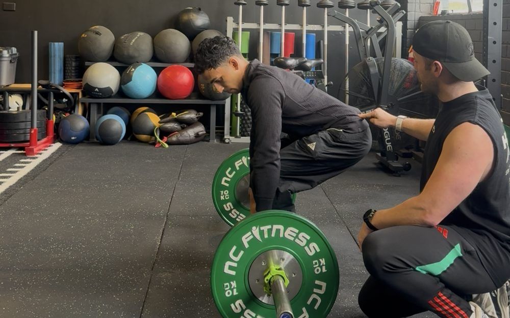 Dan cueing a client's deadlift setup at Hustle Wellness Club